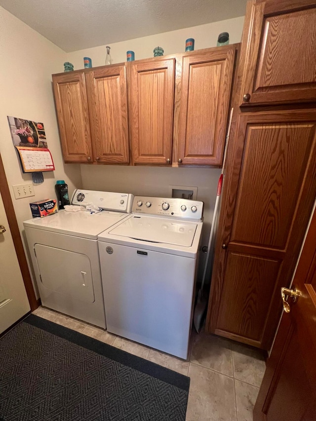 laundry room featuring washer and dryer, light tile patterned flooring, and cabinets