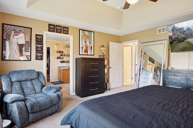 bedroom featuring ceiling fan, light colored carpet, and ensuite bathroom