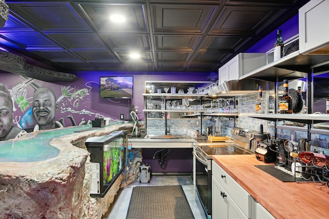 interior space with electric stove, white cabinetry, and wood counters