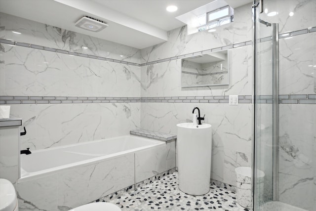 bathroom with toilet, tile walls, and independent shower and bath