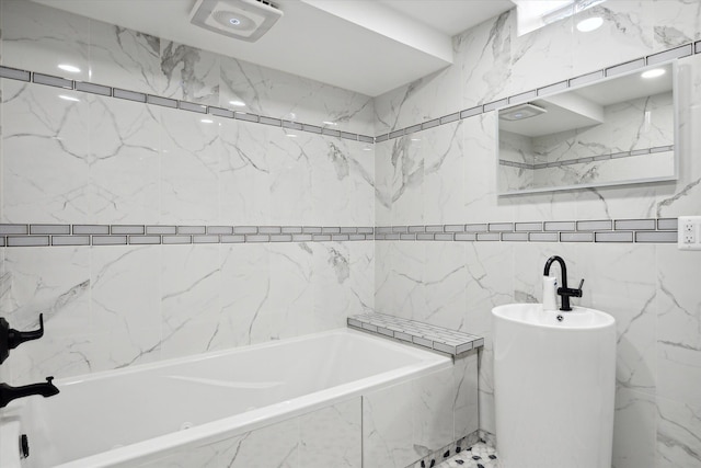 bathroom with tiled tub and tile walls