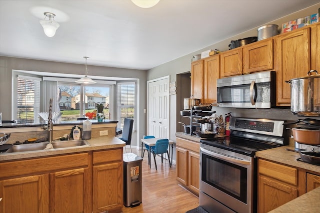 kitchen featuring a wealth of natural light, sink, stainless steel appliances, and light hardwood / wood-style floors