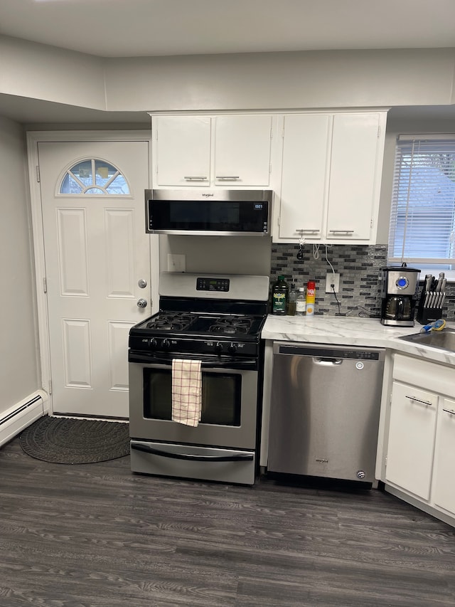 kitchen with appliances with stainless steel finishes, tasteful backsplash, dark wood-type flooring, sink, and white cabinetry