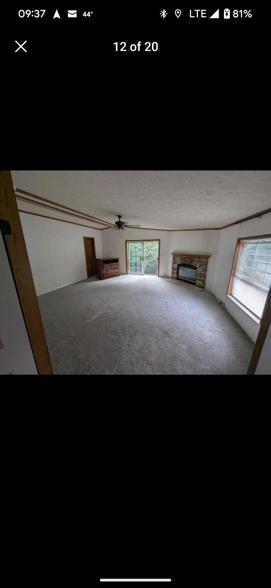 unfurnished living room featuring ceiling fan, carpet floors, and a textured ceiling