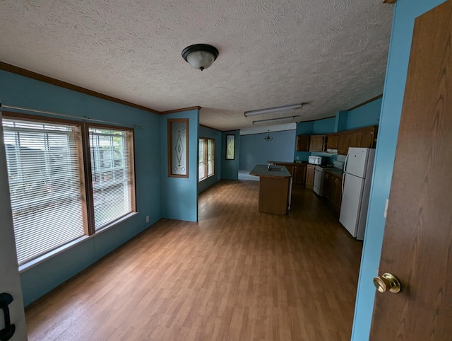 kitchen with hardwood / wood-style flooring, a kitchen island, white appliances, and a textured ceiling