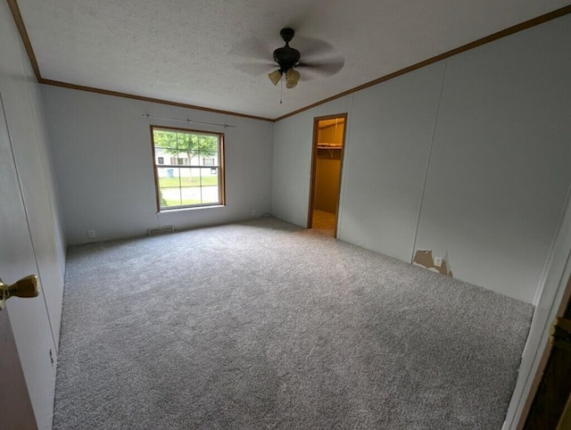 carpeted spare room featuring a textured ceiling, ceiling fan, and ornamental molding