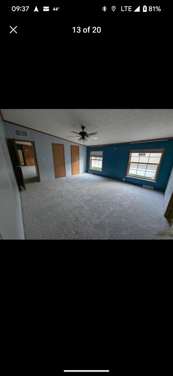 interior space with carpet, ceiling fan, and a textured ceiling