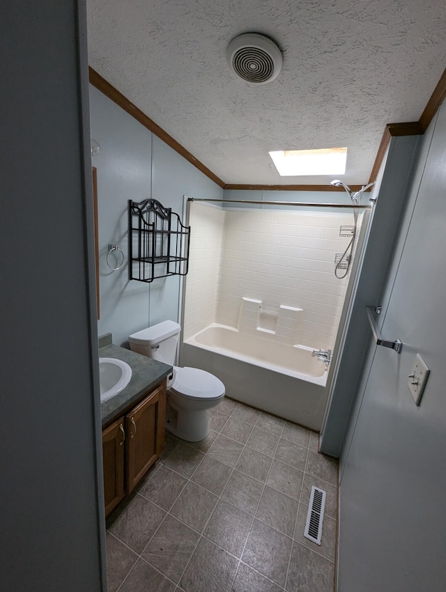 full bathroom featuring a skylight, vanity, a textured ceiling, tiled shower / bath combo, and toilet