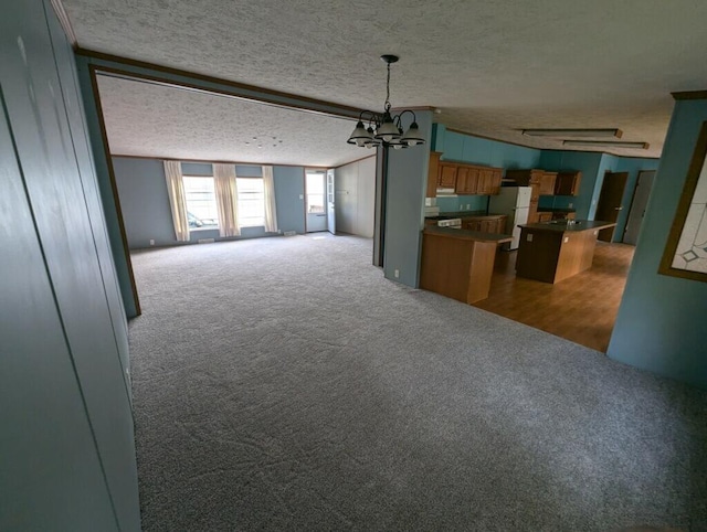 unfurnished living room with carpet flooring, a textured ceiling, and an inviting chandelier