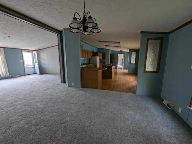 unfurnished living room featuring light carpet, a chandelier, a textured ceiling, and ornamental molding