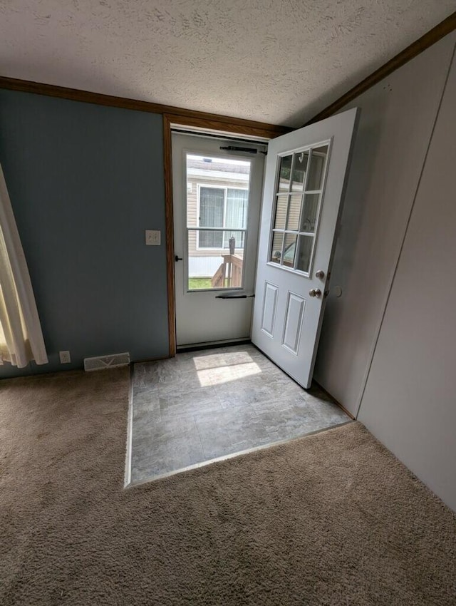 doorway to outside with light colored carpet, a textured ceiling, and ornamental molding