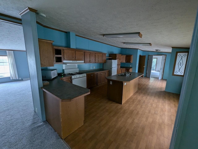 kitchen featuring white appliances, a textured ceiling, a center island, and dark wood-type flooring