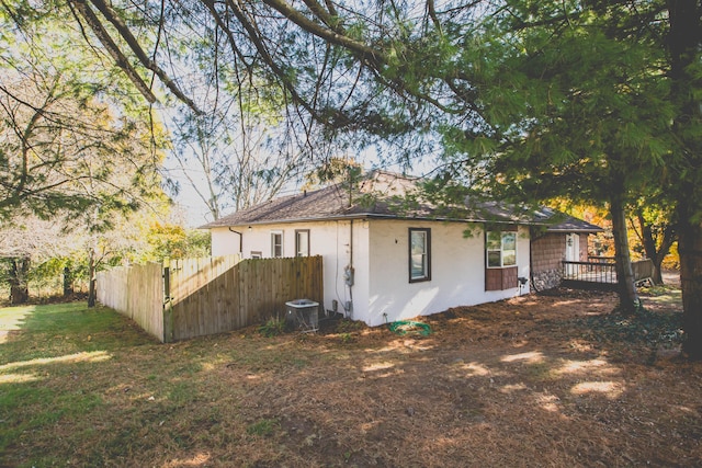 view of side of home with a lawn, cooling unit, and a deck