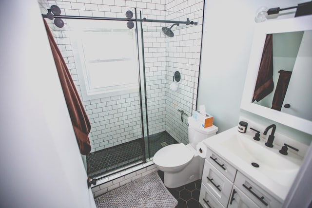 bathroom featuring tile patterned flooring, vanity, toilet, and a shower with door