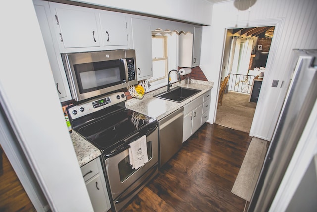 kitchen with light stone countertops, dark hardwood / wood-style flooring, stainless steel appliances, sink, and white cabinets