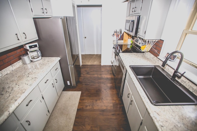 kitchen with light stone counters, sink, stainless steel appliances, and dark hardwood / wood-style floors