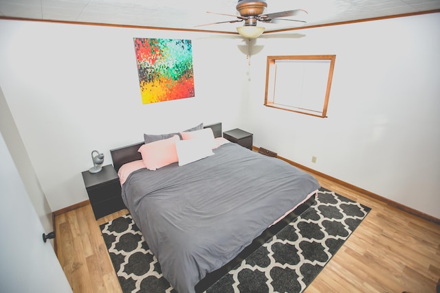 bedroom with hardwood / wood-style flooring, ceiling fan, and ornamental molding