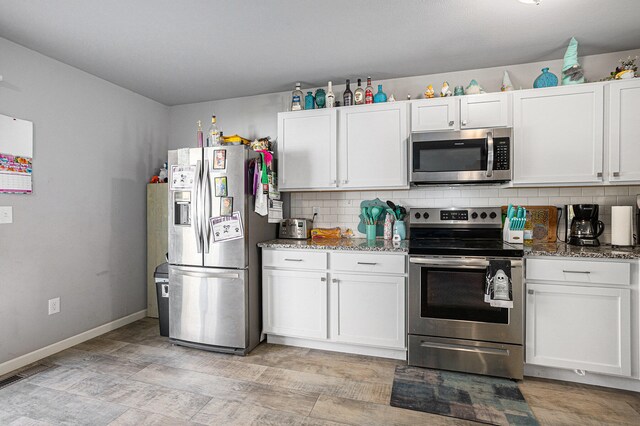 kitchen featuring white cabinets, stainless steel appliances, dark stone counters, and tasteful backsplash