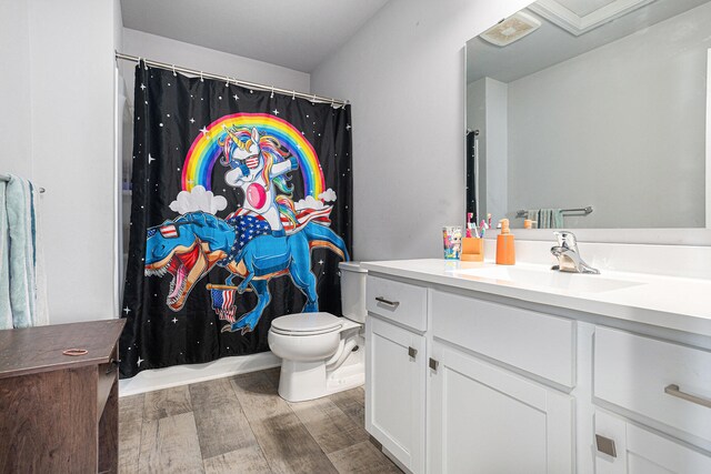 bathroom with hardwood / wood-style flooring, vanity, toilet, and walk in shower