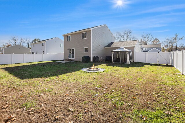 back of property featuring a fire pit and a yard