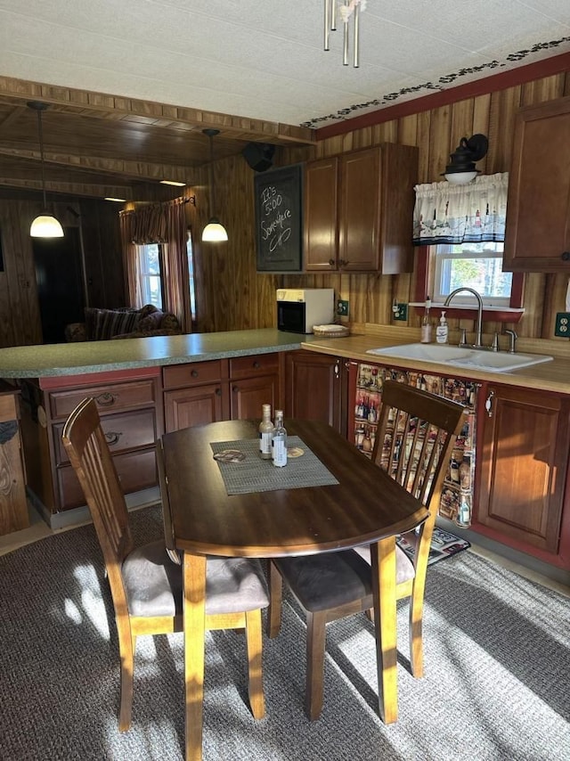 carpeted dining room with a textured ceiling, sink, and wood walls