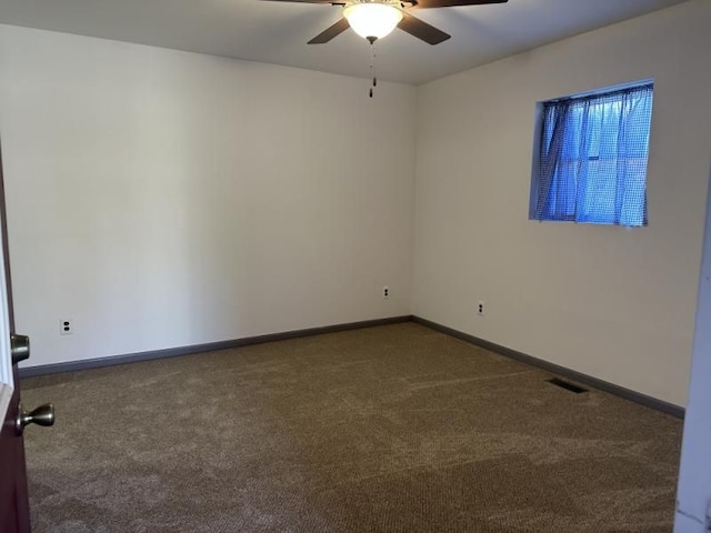 spare room featuring dark colored carpet and ceiling fan