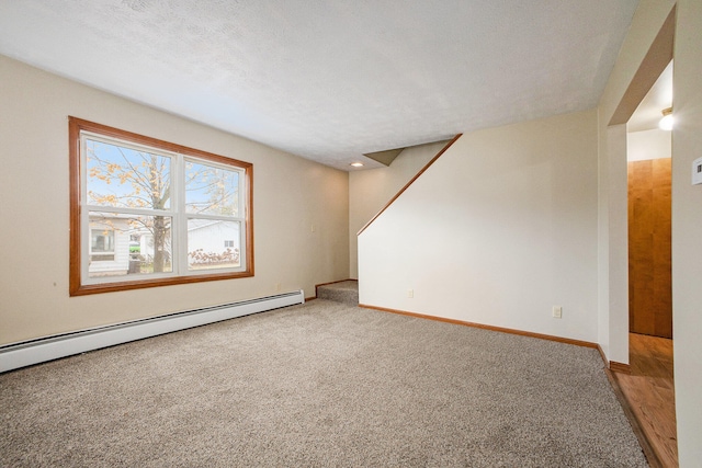 carpeted spare room with a baseboard radiator and a textured ceiling