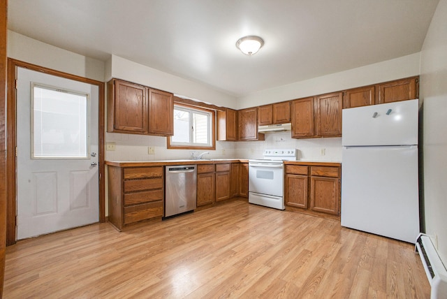 kitchen featuring light wood-type flooring, backsplash, white appliances, baseboard heating, and sink