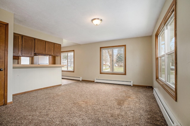 unfurnished living room featuring a textured ceiling, baseboard heating, and light carpet