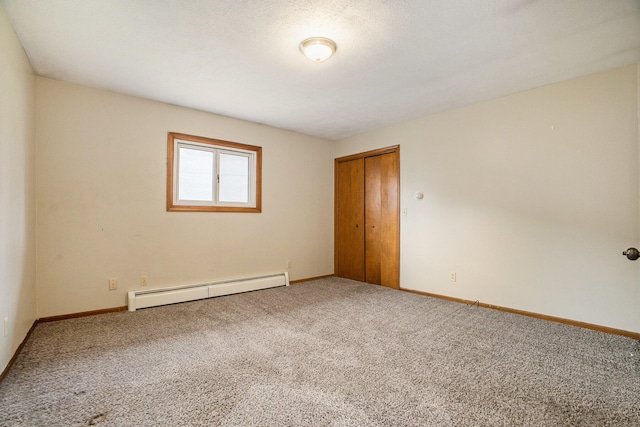 carpeted empty room with a textured ceiling and a baseboard heating unit