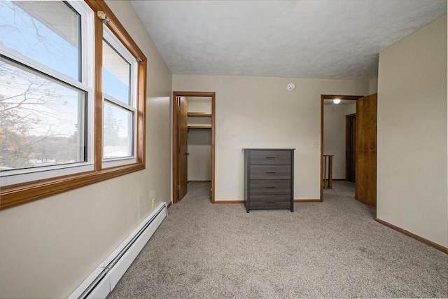 unfurnished bedroom featuring light carpet, a walk in closet, a baseboard radiator, and a closet