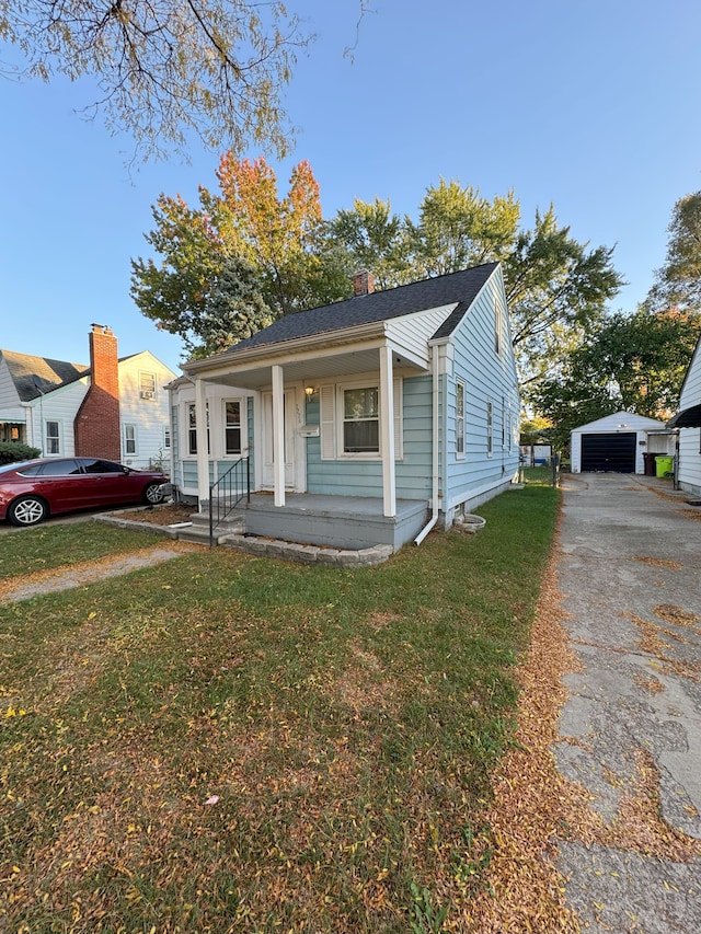 bungalow-style home with covered porch, an outbuilding, and a front yard