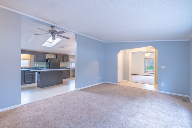 unfurnished living room with light carpet, a textured ceiling, and crown molding