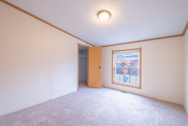 unfurnished bedroom featuring crown molding, vaulted ceiling, a textured ceiling, a closet, and carpet