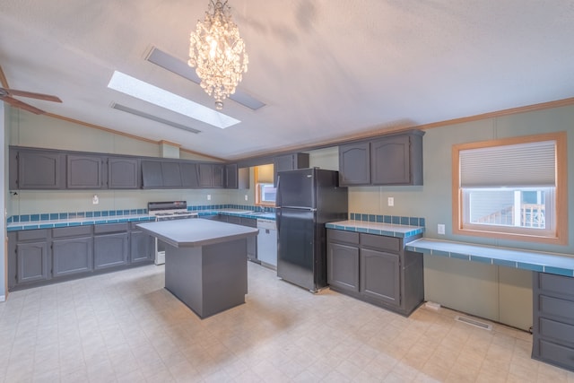 kitchen featuring black fridge, lofted ceiling with skylight, dishwasher, a kitchen island, and stainless steel range with electric cooktop