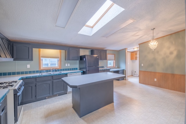 kitchen featuring a skylight, a chandelier, pendant lighting, a kitchen island, and appliances with stainless steel finishes