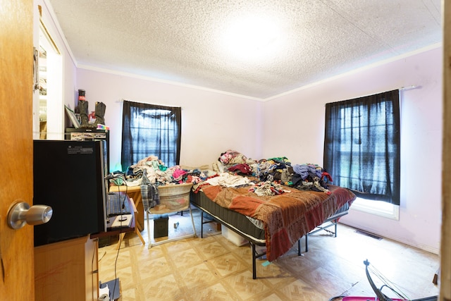 bedroom with multiple windows, light parquet flooring, a textured ceiling, and ornamental molding