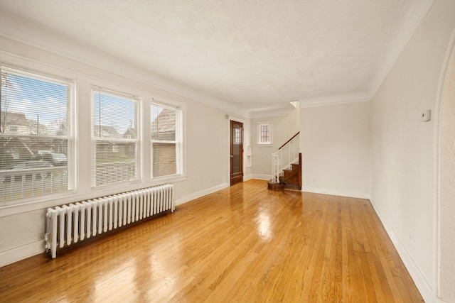 spare room featuring light hardwood / wood-style floors, crown molding, and radiator