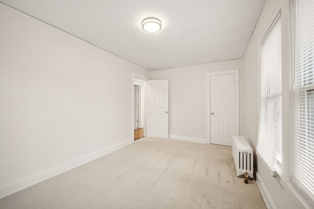 unfurnished bedroom with light colored carpet and radiator