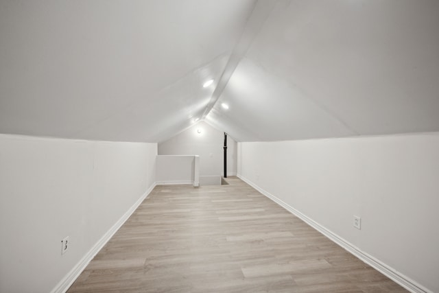 bonus room with light wood-type flooring and vaulted ceiling