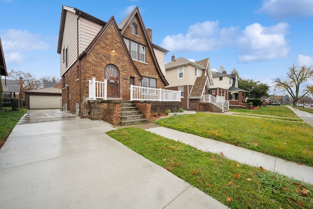 english style home with a garage, an outbuilding, and a front lawn