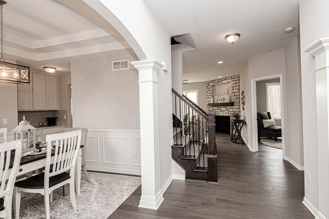 interior space featuring a stone fireplace, hardwood / wood-style floors, and ornate columns