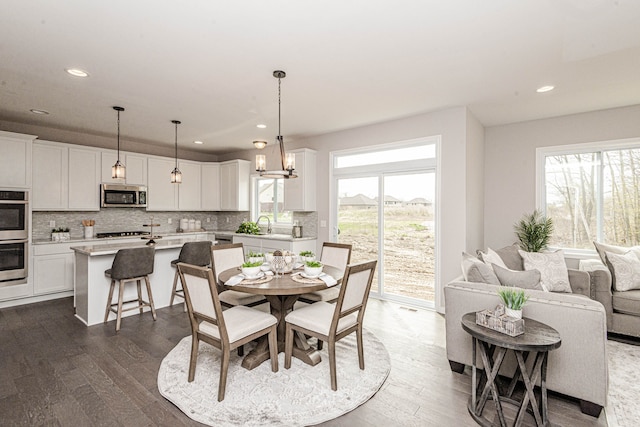 dining area with an inviting chandelier, sink, dark hardwood / wood-style floors, and a healthy amount of sunlight