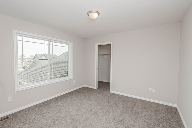 unfurnished bedroom featuring a spacious closet, light colored carpet, and a closet