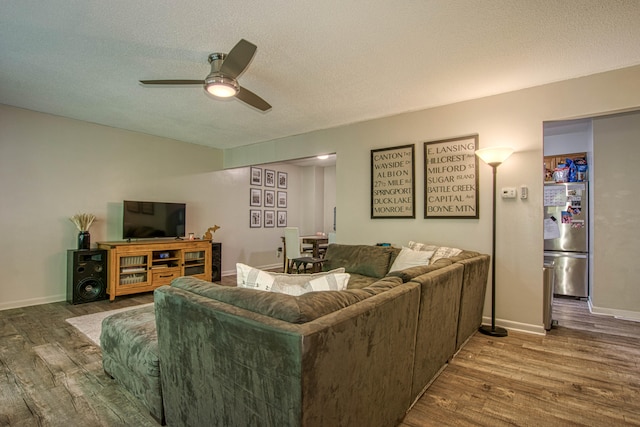 living room with ceiling fan, a textured ceiling, and hardwood / wood-style flooring