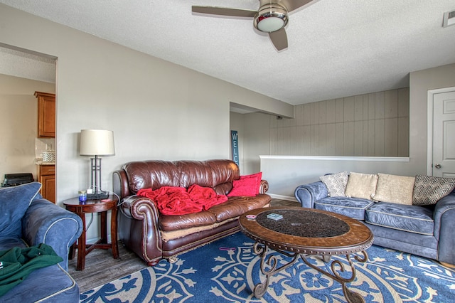 living room with a textured ceiling, dark hardwood / wood-style flooring, and ceiling fan