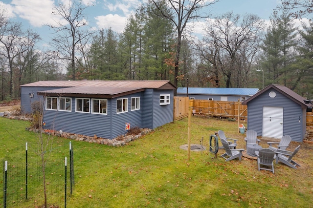 back of property featuring a shed, a yard, and a fire pit