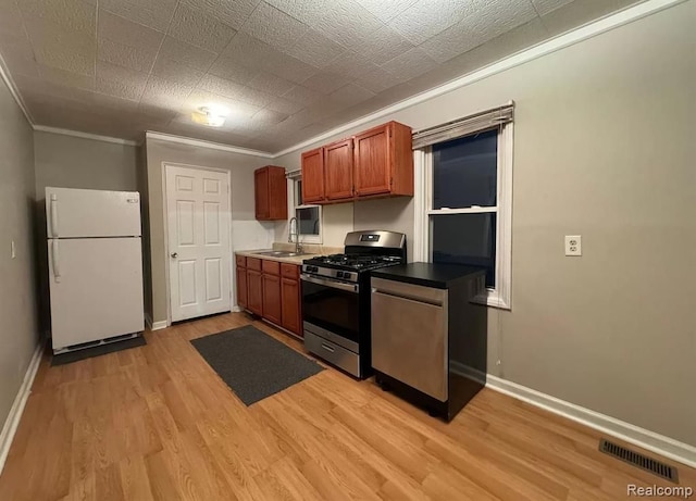 kitchen with sink, light wood-type flooring, white fridge, and stainless steel range with gas stovetop