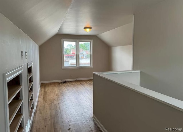 additional living space with vaulted ceiling and hardwood / wood-style flooring