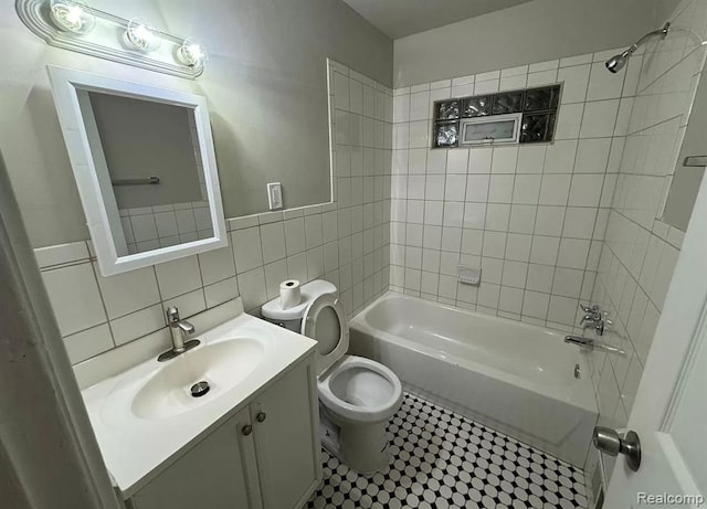 full bathroom featuring vanity, tiled shower / bath combo, toilet, and tile walls